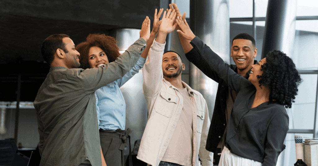 A diverse group of professionals smiling and giving high-fives, symbolizing team success and collaboration.