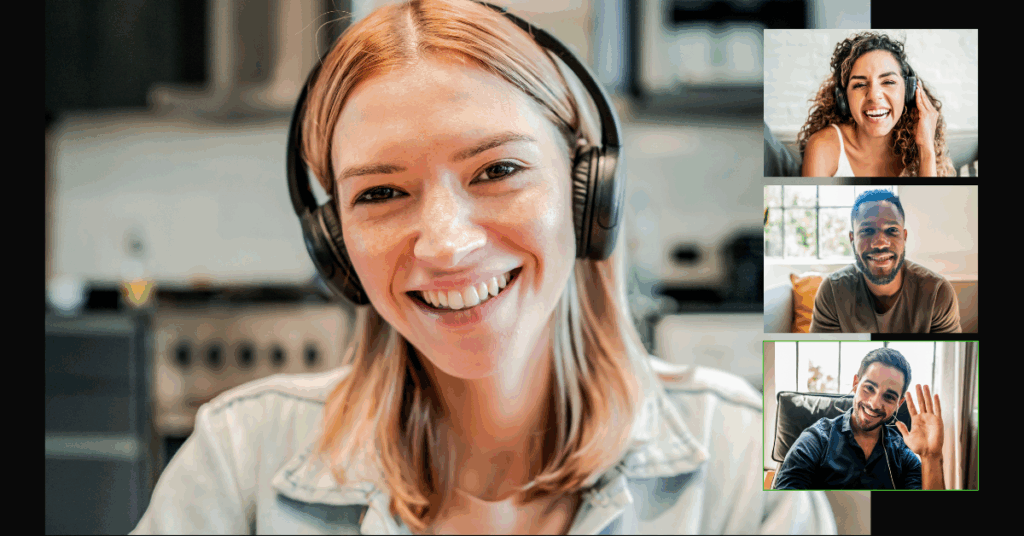 Woman smiling with headphones on, talking in a group video call with three other remote professionals.
