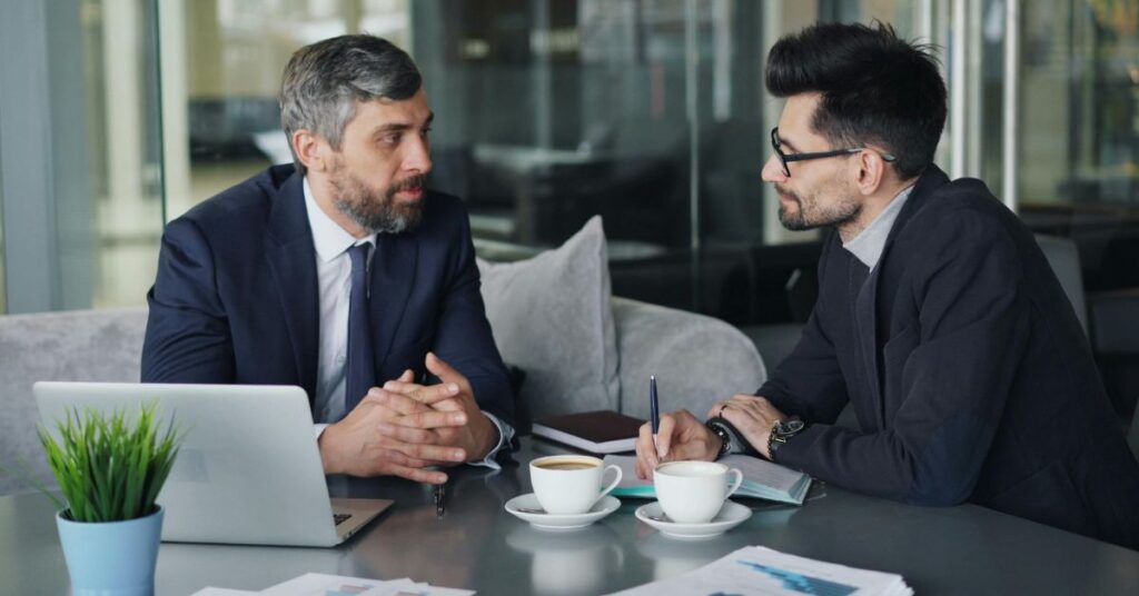 Two business professionals discussing predictive insights over coffee in a modern office setting.