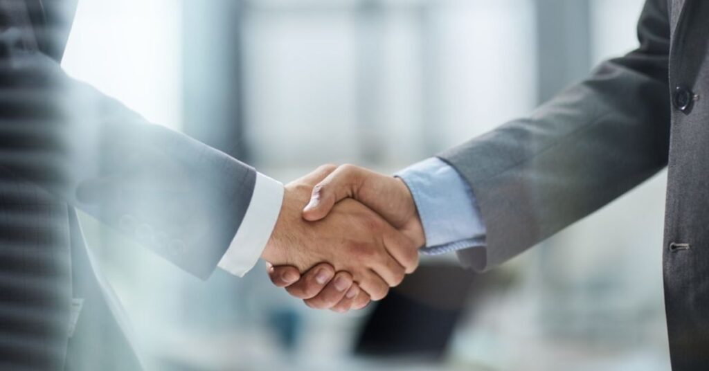 Business professionals shaking hands, symbolizing a partnership with an offshore AI development company.