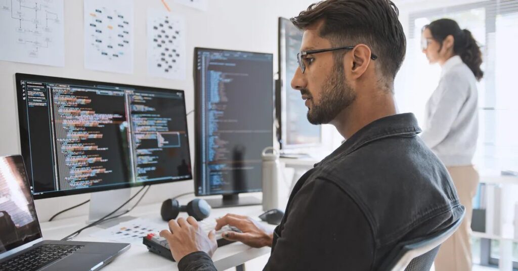 Software engineer coding on multiple screens, developing AI applications using advanced frameworks and tools.