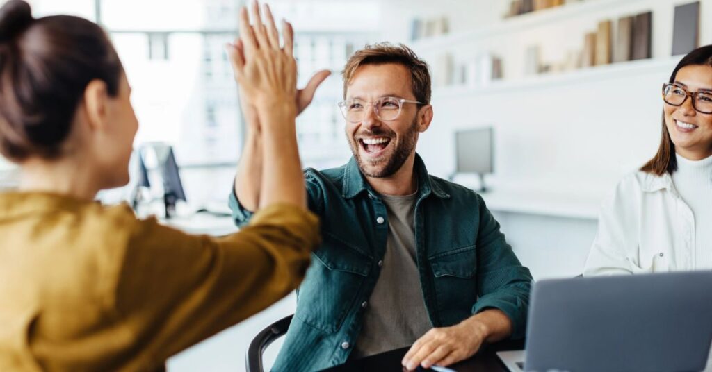 Team members celebrating success with a high-five during an AI project meeting.