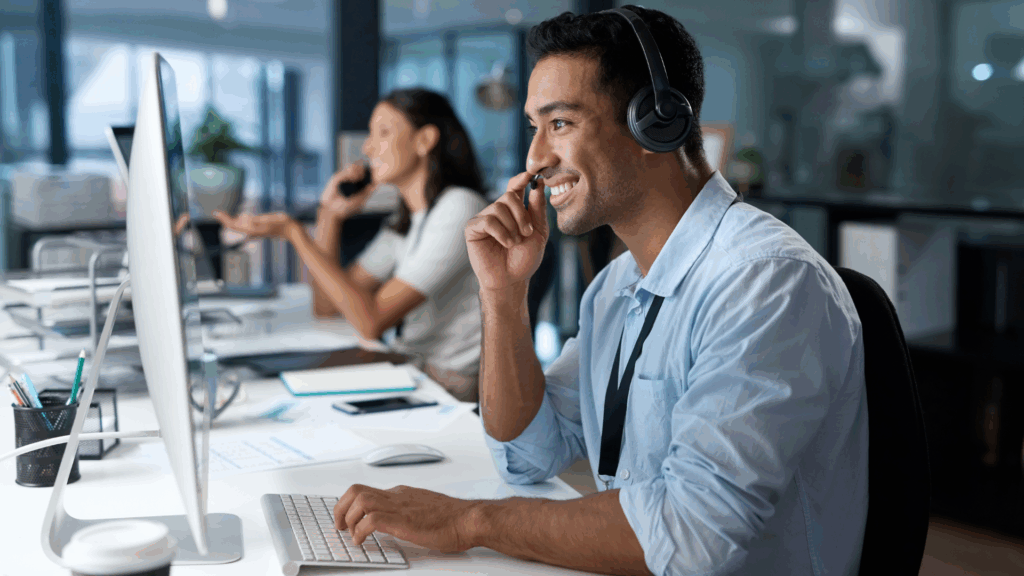 Smiling customer service representative using a headset at a computer, emphasizing smooth international collaboration.