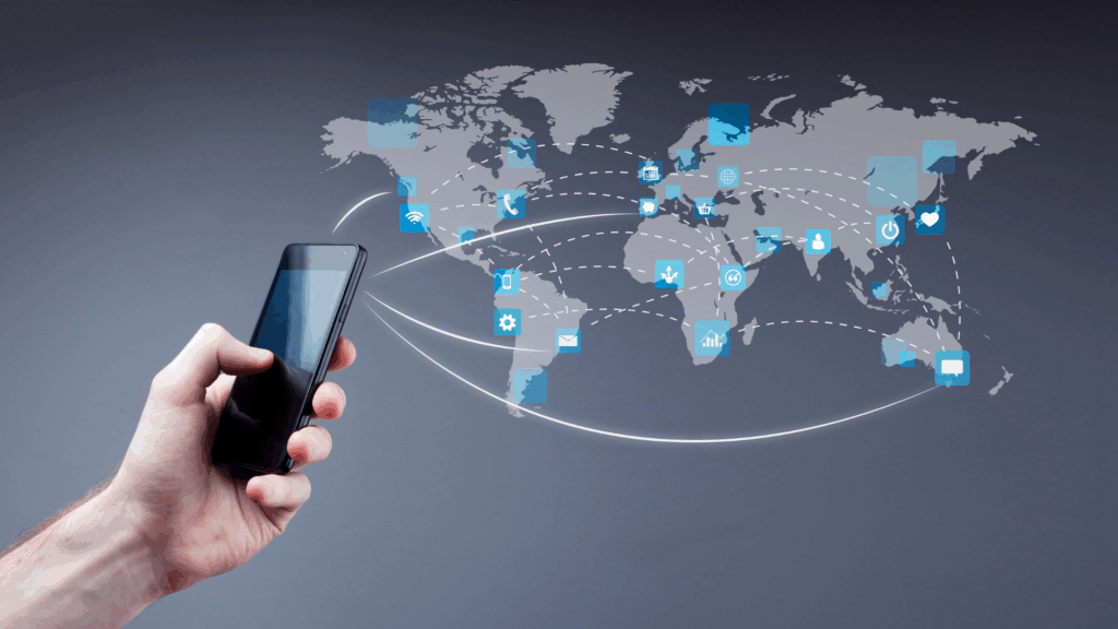 Hand holding smartphone with icons and global connection lines over a digital world map, representing remote team connectivity.