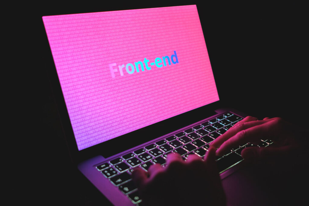 parallelstaff- Hands typing on a laptop with a pink screen displaying "Front-end" in bold, multicolored text, symbolizing web development or programming—perfect for illustrating guides on how to hire a front end developer.