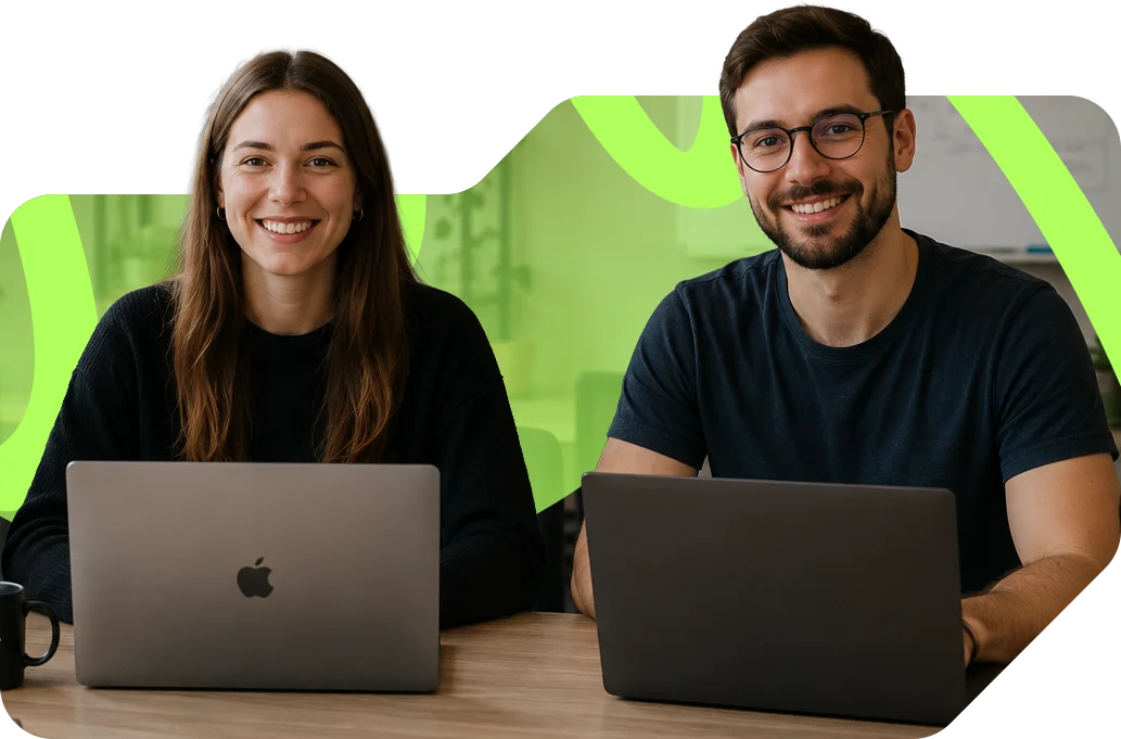 parallelstaff- Two people sitting at a table, smiling and facing the camera, each working on a laptop. The background features a light green abstract shape.