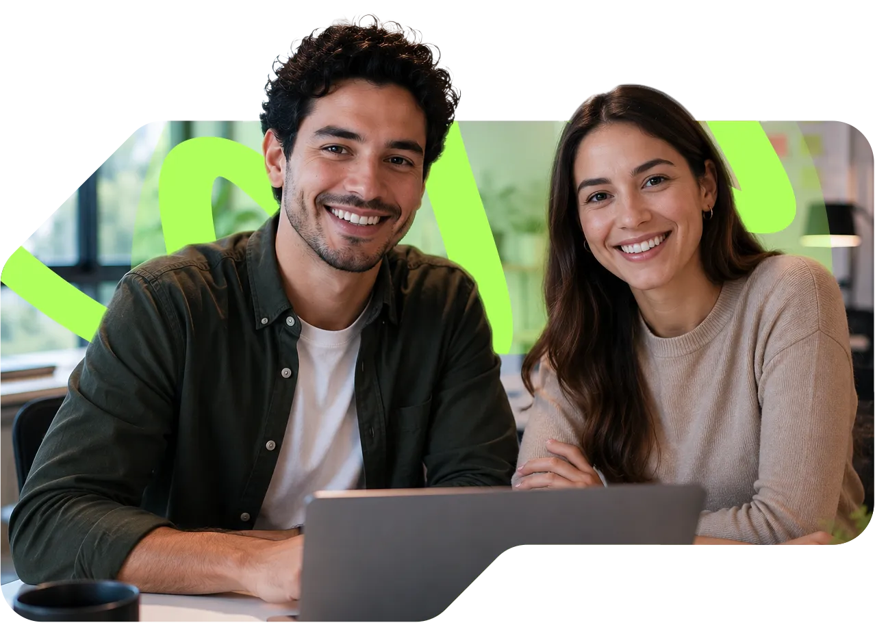 parallelstaff- Two people, a man and a woman, sit together at a table smiling at the camera with a laptop in front of them and a bright green abstract design in the background.