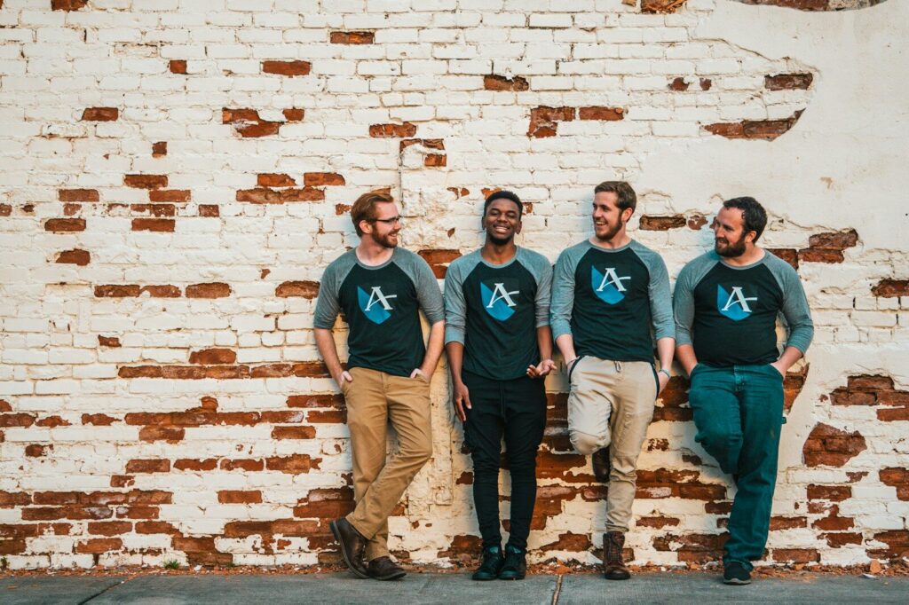 a group of men standing next to a brick wall