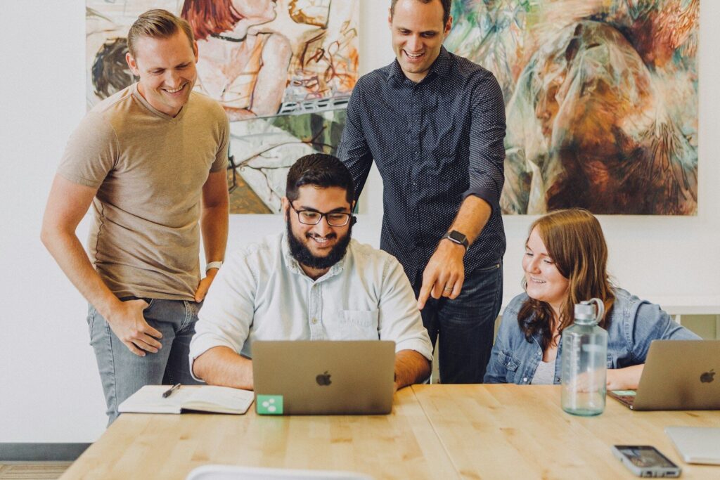 four coworkers smiling around laptop at table