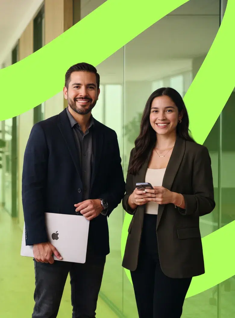 parallelstaff- Two professionals, a man holding a laptop and a woman holding a smartphone, stand smiling in an office with large glass walls and green graphic accents.