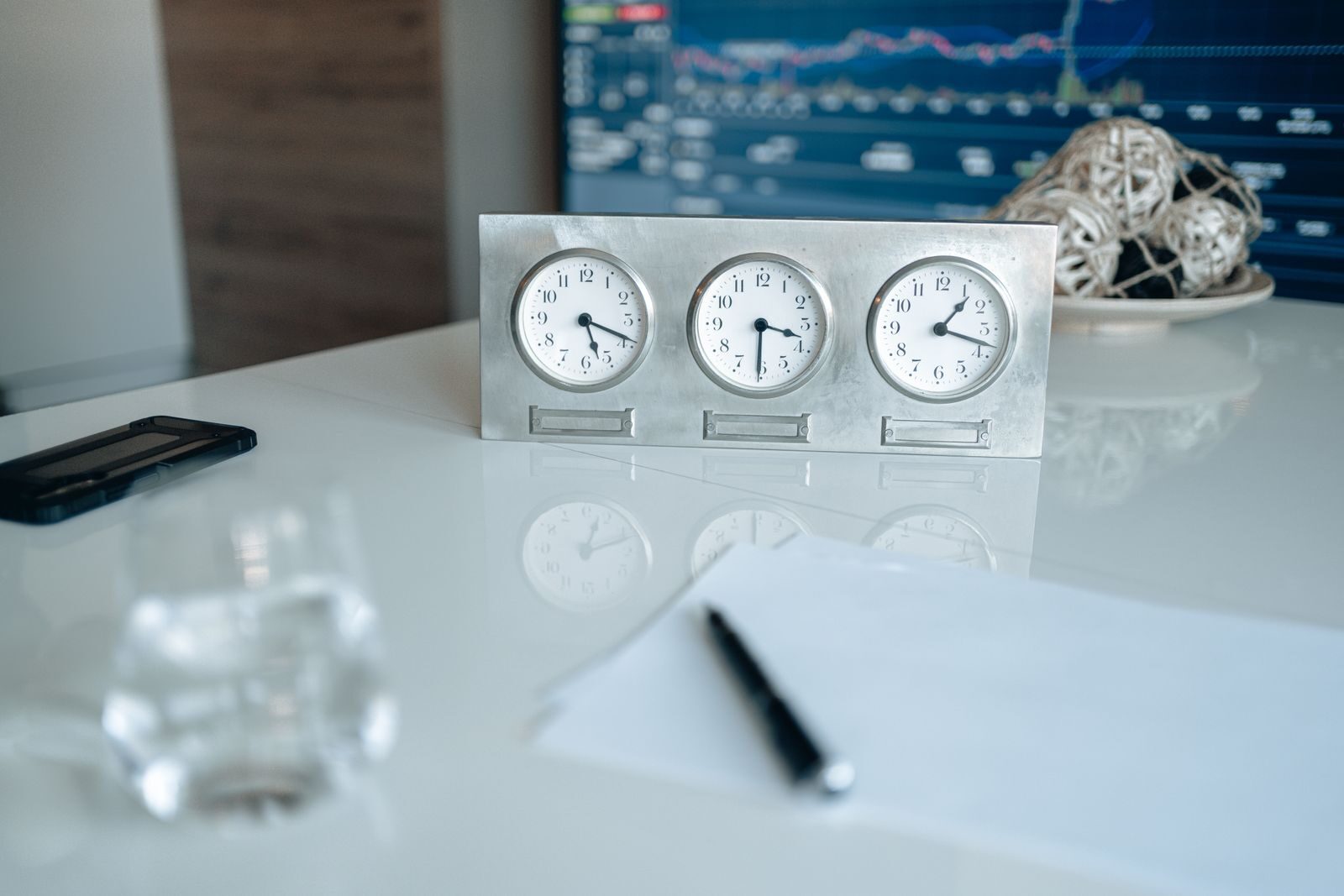 Professional workspace featuring three clocks and financial data on screen.